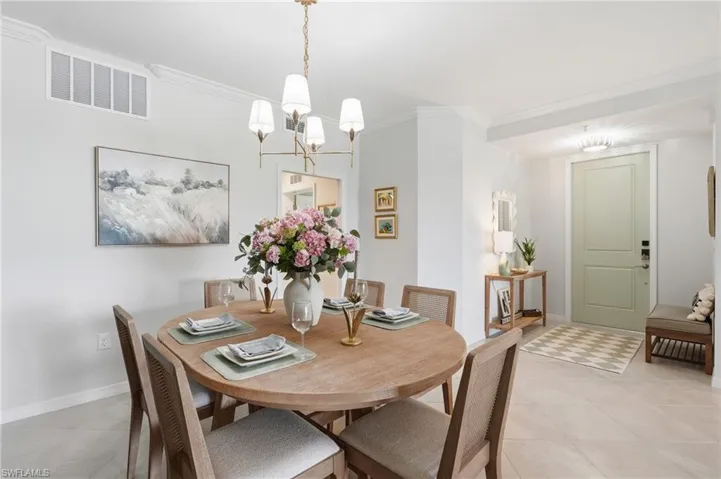 Dining area featuring a contemporary chandelier, crown molding, and light-toned flooring