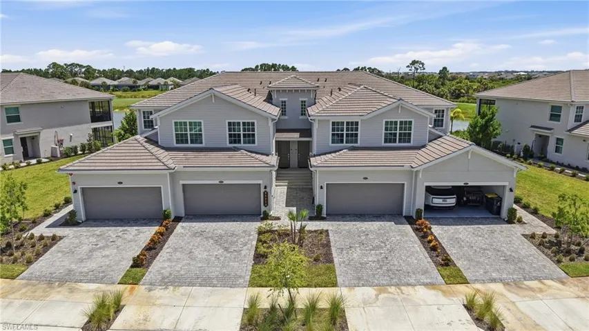 Modern multi-unit residence featuring light gray siding, tiled roofing, and paver driveways