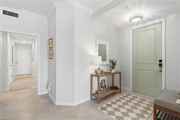 Entry foyer featuring a paneled door, crown molding, and large format tile flooring