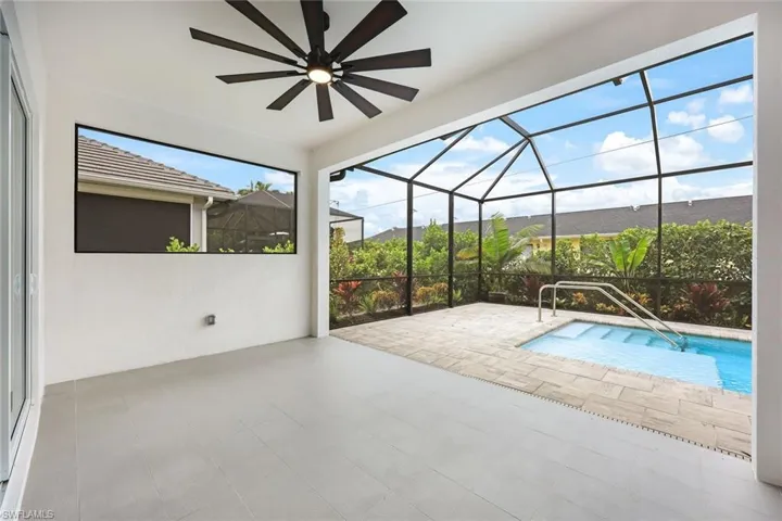 View of pool featuring glass enclosure, ceiling fan, and a patio area