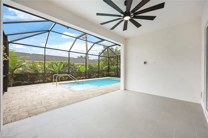 View of pool with a patio, ceiling fan, and glass enclosure