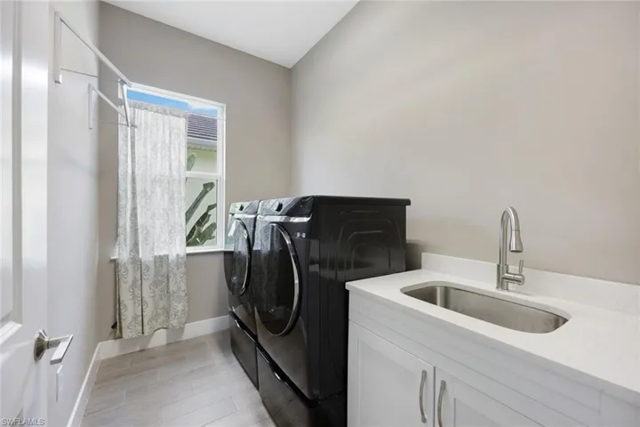 Laundry area featuring cabinets, light hardwood / wood-style floors, independent washer and dryer, and sink