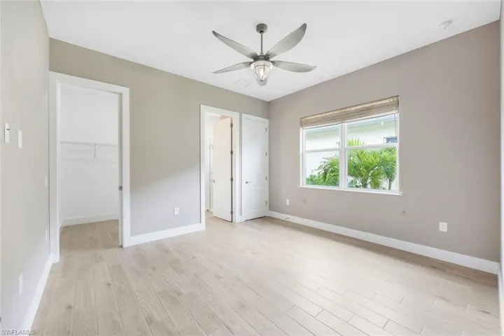 Unfurnished bedroom featuring a spacious closet, light hardwood / wood-style flooring, a closet, and ceiling fan