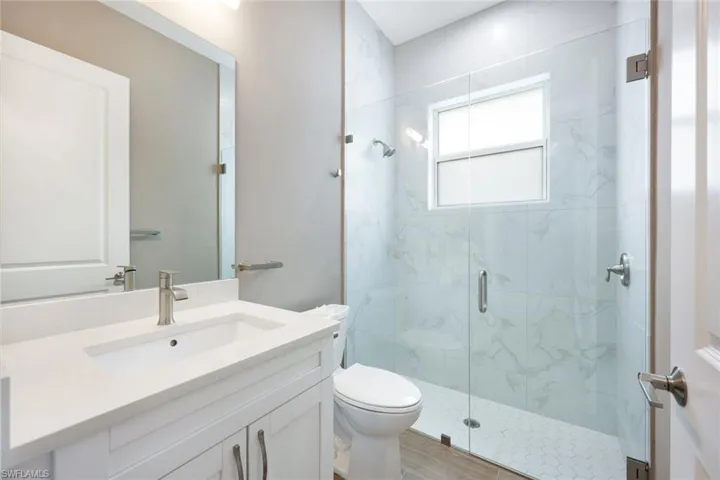 Bathroom with a shower with door, toilet, vanity, and hardwood / wood-style flooring