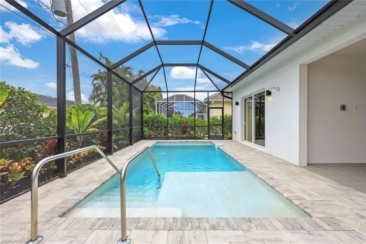 View of pool featuring glass enclosure and a patio area