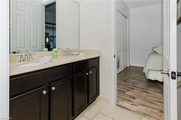 Ensuite bathroom featuring double vanity and wood finished floors