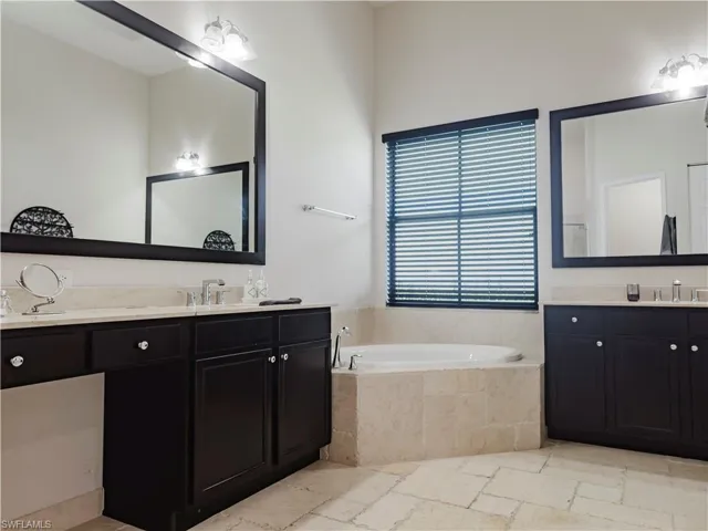 Bathroom with two vanities, a garden tub, and stone tile floors