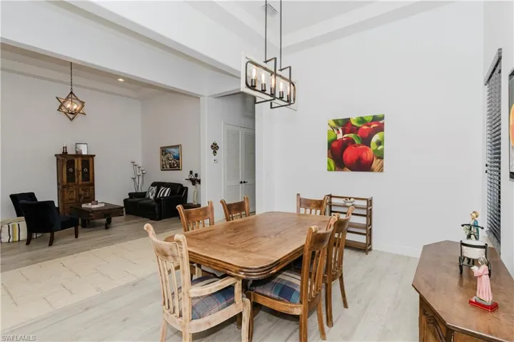 Dining space featuring light wood finished floors, a chandelier, and beamed ceiling