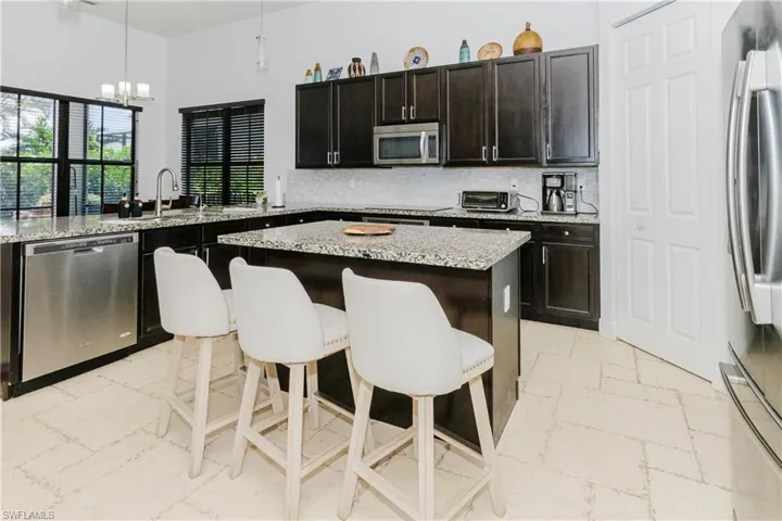 Kitchen with appliances with stainless steel finishes, a chandelier, a breakfast bar, a kitchen island, and hanging light fixtures