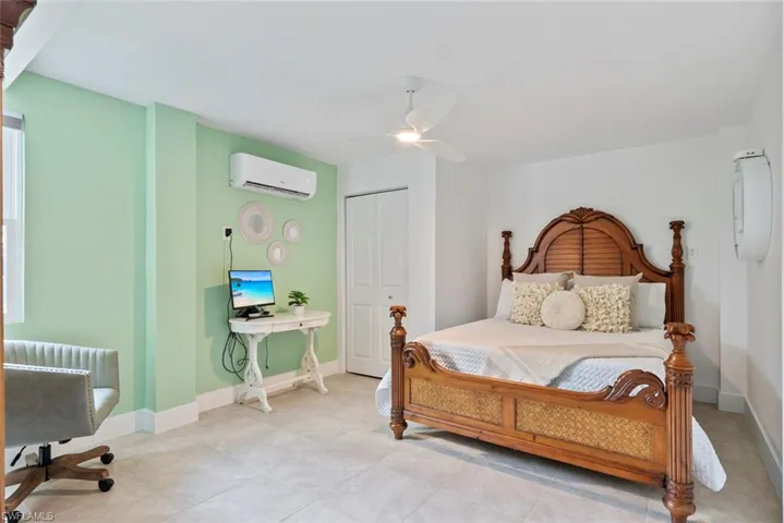 Bedroom with an AC wall unit, baseboards, ceiling fan, and light tile patterned flooring