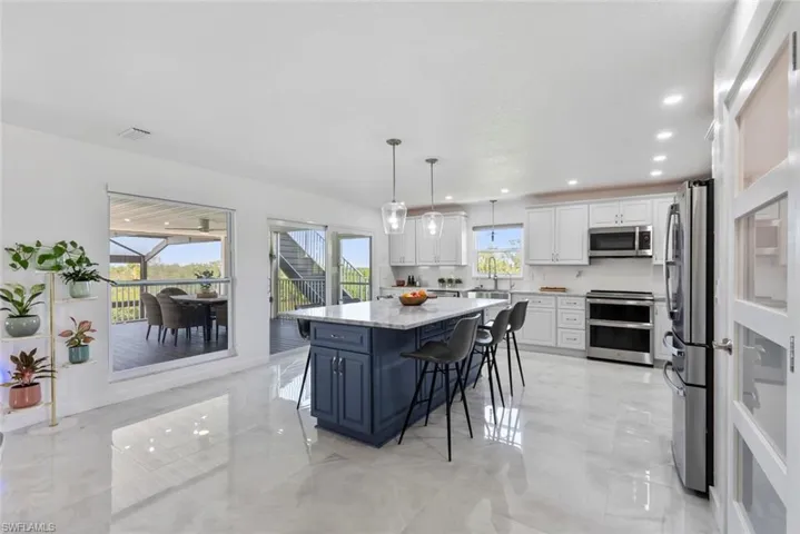 Kitchen featuring white cabinets, a breakfast bar area, marble finish floor, stainless steel appliances, and visible vents