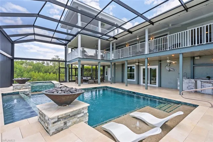 Pool with an outdoor hot tub, a ceiling fan, exterior kitchen, a patio area, and glass enclosure
