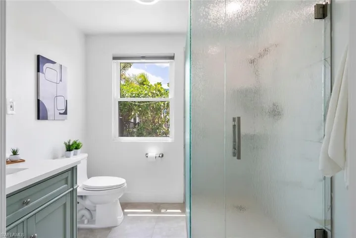 Full bathroom featuring toilet, tile patterned floors, a shower stall, and vanity