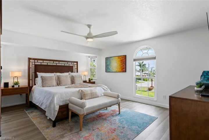 Bedroom with ceiling fan, baseboards, multiple windows, and wood finished floors
