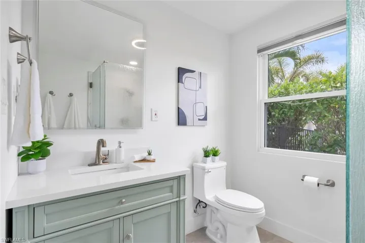Bathroom featuring a shower with shower door, vanity, baseboards, tile patterned floors, and toilet