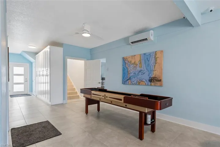 Rec room with baseboards, a wall unit AC, and a ceiling fan