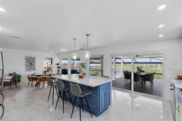 Kitchen featuring recessed lighting, blue cabinetry, a breakfast bar, and light stone counters