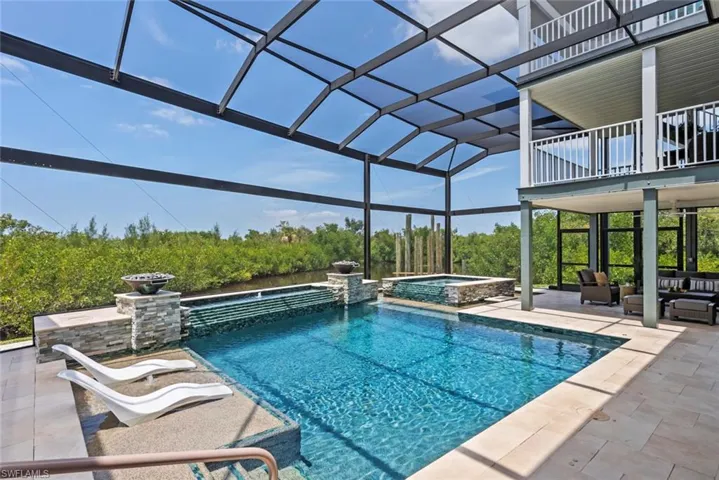 View of pool with a lanai, a patio, a pool with connected hot tub, and outdoor lounge area