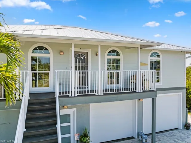 View of exterior entry with a garage, covered porch, driveway, and metal roof