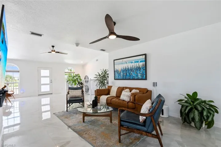 Living area with ceiling fan, lofted ceiling, marble finish floor, and visible vents