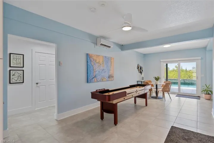 Playroom featuring baseboards, a ceiling fan, light tile patterned floors, and a wall unit AC