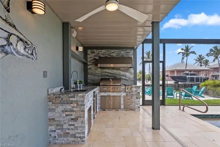 View of patio featuring a sink, exterior kitchen, grilling area, and a ceiling fan