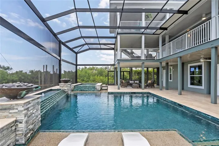 View of pool with an outdoor living space, a ceiling fan, a pool with connected hot tub, a patio area, and glass enclosure