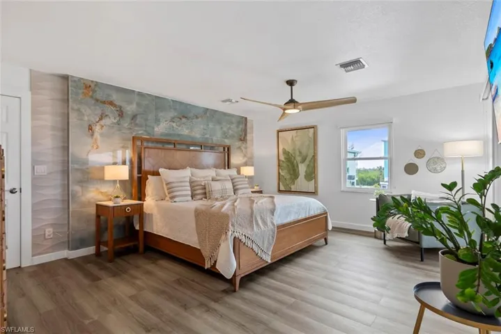Bedroom featuring visible vents, a ceiling fan, baseboards, and wood finished floors