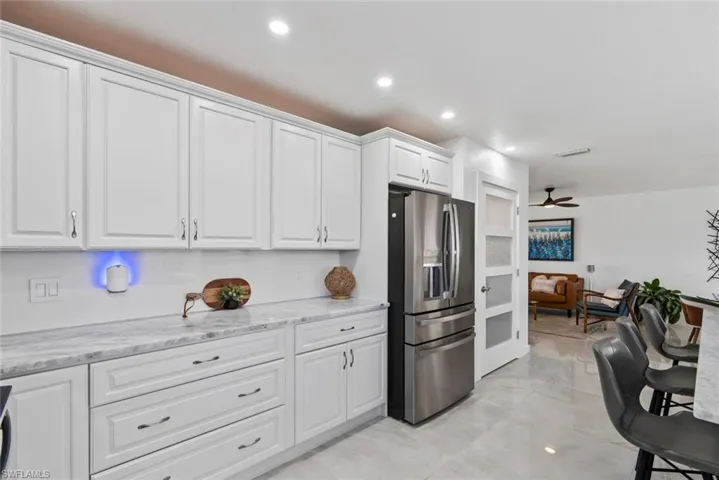 Kitchen featuring recessed lighting, white cabinets, stainless steel refrigerator with ice dispenser, and marble finish floor