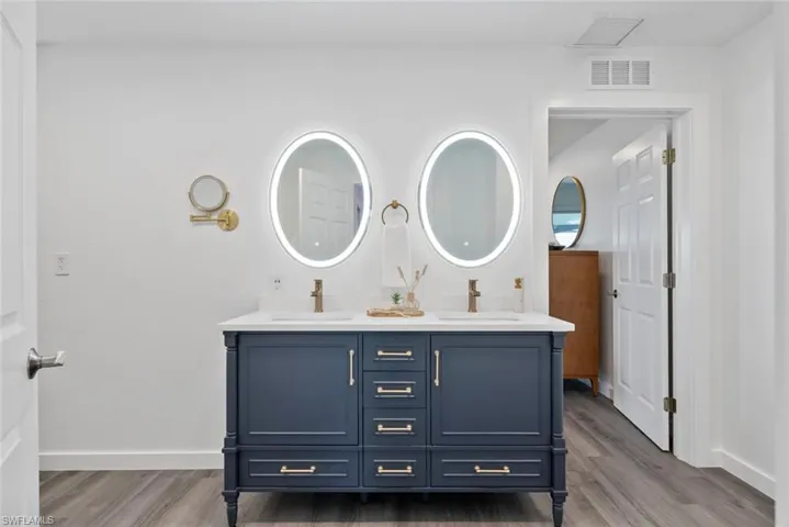 Full bathroom with visible vents, a sink, and wood finished floors
