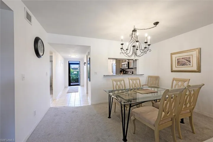 Dining space featuring light carpet and a chandelier