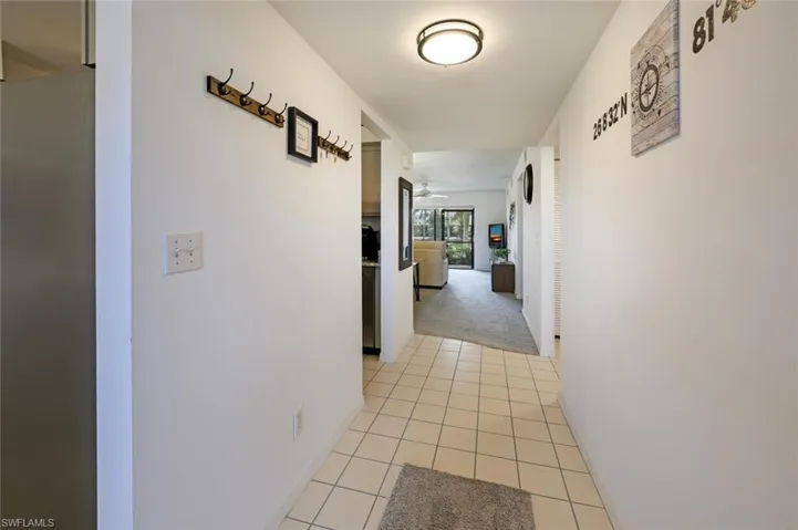Hallway featuring light tile patterned floors and light colored carpet