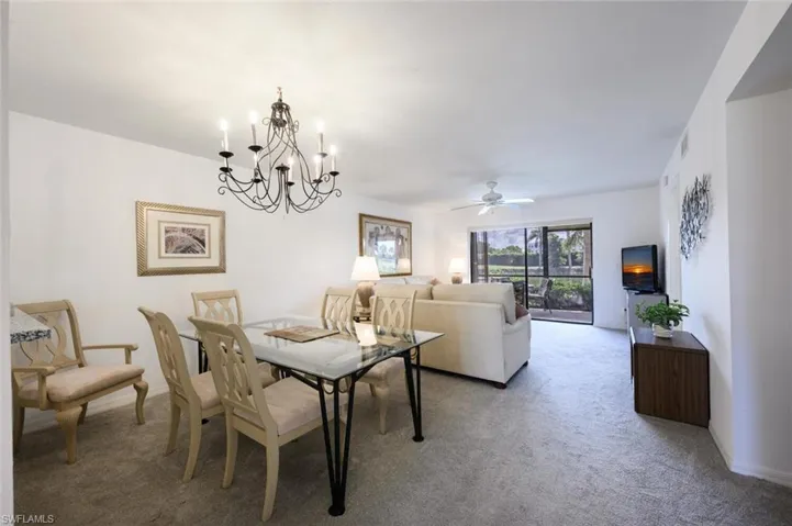 Dining room featuring light colored carpet, a chandelier, and a ceiling fan
