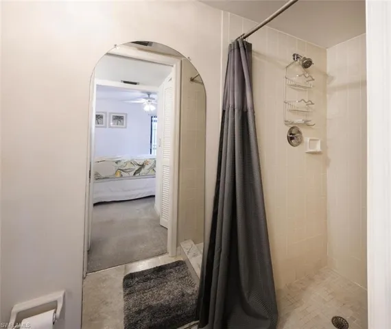 Full bathroom featuring ensuite bath, a stall shower, and a ceiling fan