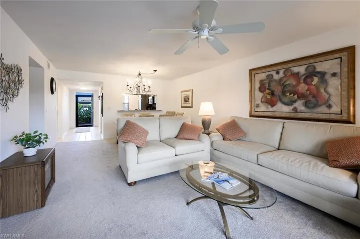 Living room featuring a chandelier, carpet flooring, and ceiling fan