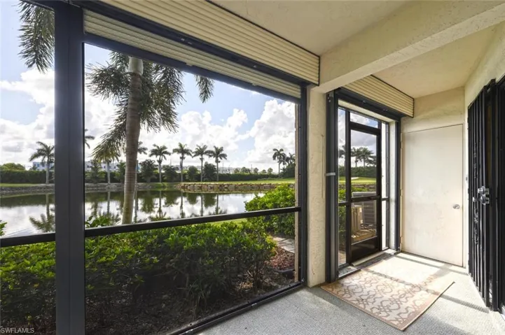 Unfurnished sunroom featuring a water view and view of scattered trees