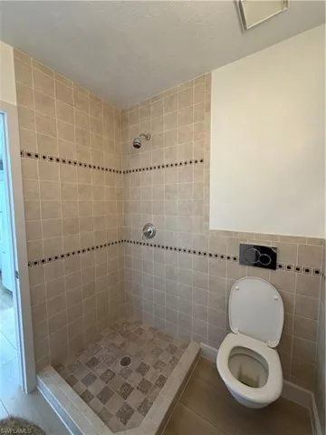 Full bath featuring a shower stall and tile walls