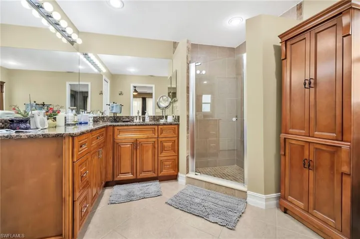 Full bath featuring a shower stall, tile patterned floors, baseboards, and vanity