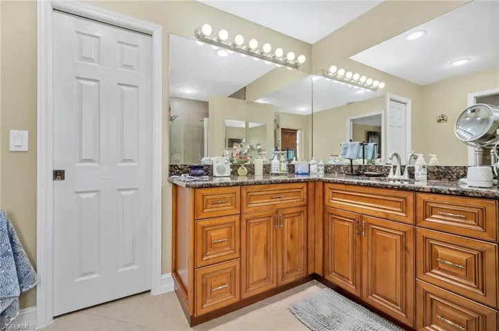Bathroom with a tile shower, tile patterned flooring, and vanity