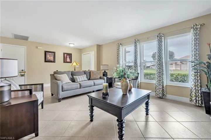 Living room featuring baseboards, visible vents, and light tile patterned floors