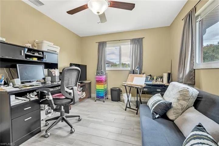 Home office featuring wood tiled floor, visible vents, baseboards, and ceiling fan