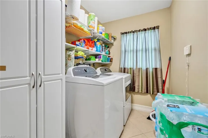 Washroom featuring baseboards, washer and clothes dryer, laundry area, and light tile patterned floors