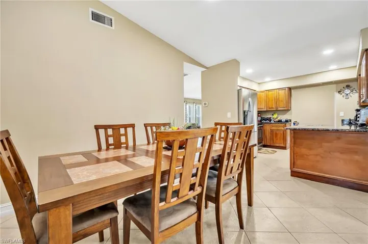 Dining space with light tile patterned floors, recessed lighting, lofted ceiling, and visible vents
