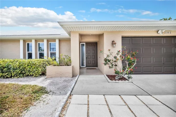 Doorway to property featuring a garage, driveway, and stucco siding