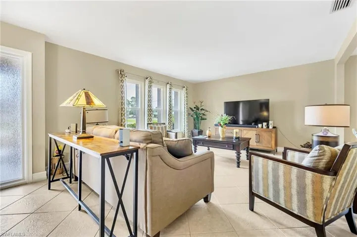 Living area featuring light tile patterned flooring, baseboards, and visible vents