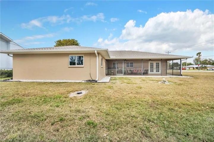 Rear view of property with stucco siding, a sunroom, ceiling fan, and a yard