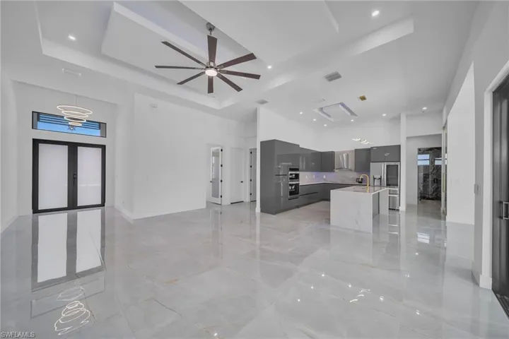 Unfurnished living room featuring ceiling fan and a tray ceiling