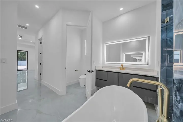 Bathroom featuring vanity, toilet, and a tub