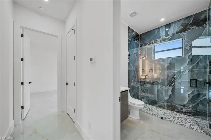 Bathroom featuring vanity, toilet, and a shower with door