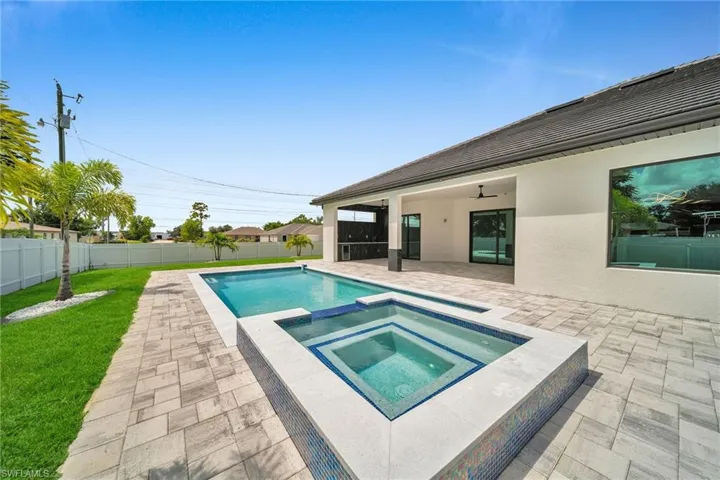 View of pool featuring a patio area, a yard, ceiling fan, and an in ground hot tub